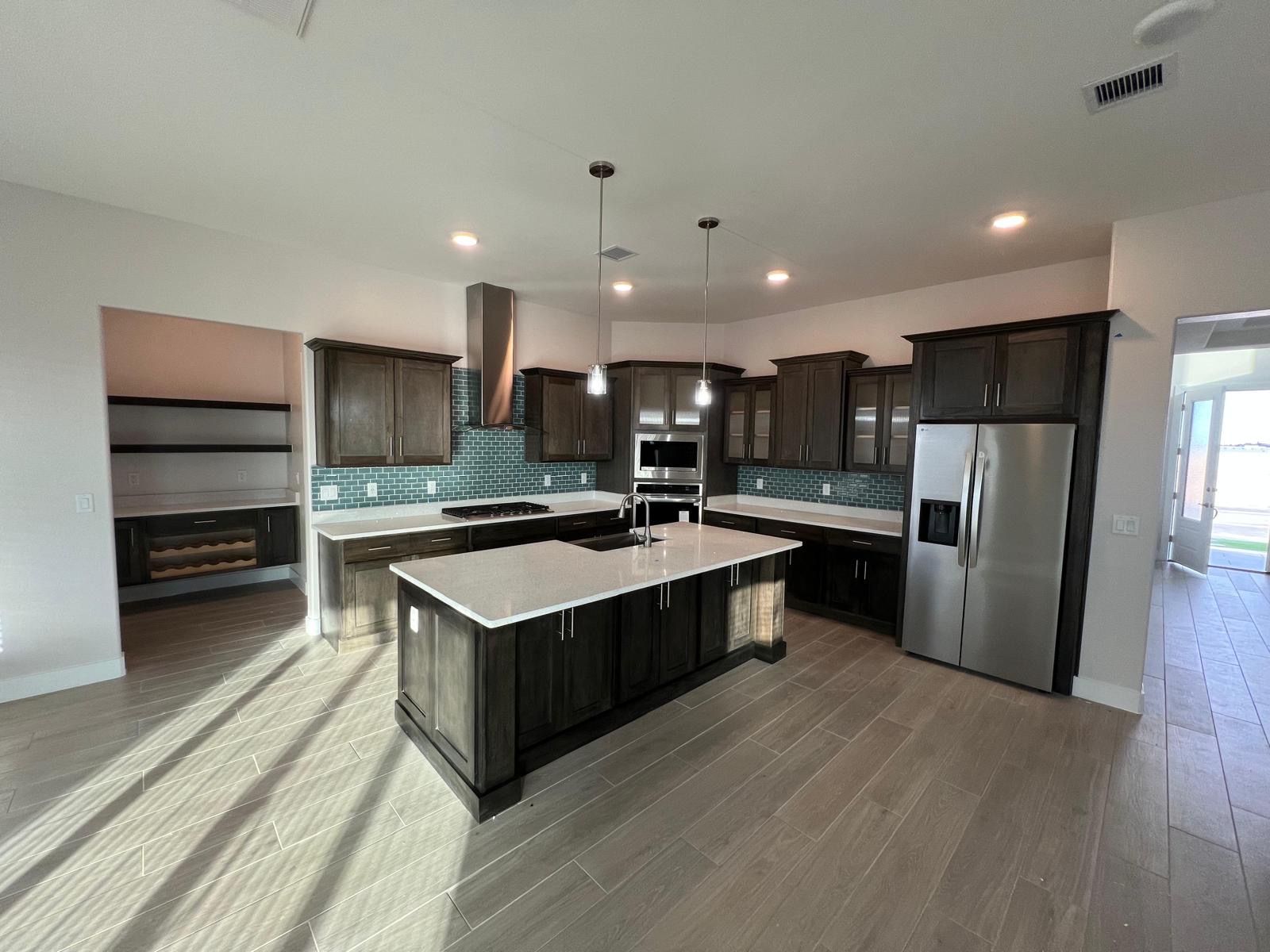 Grey stained wood kitchen cabinets with a large island and quartz countertops