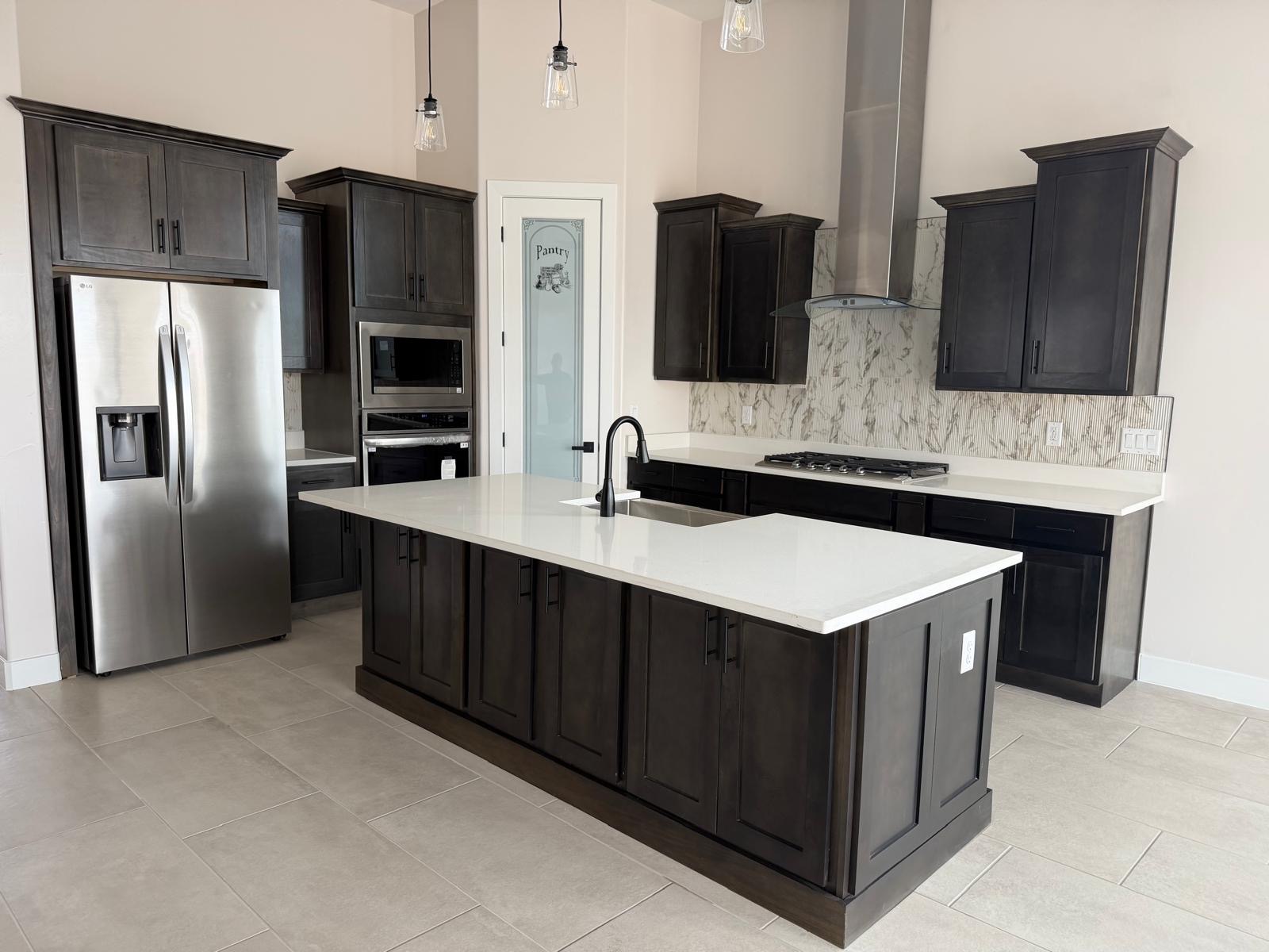 Dark stained wood kitchen cabinets with quartz island and marble backsplash