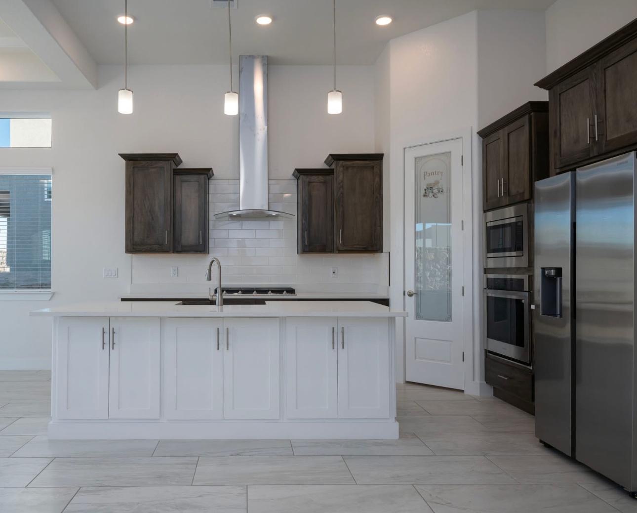 Dark stained wood upper cabinets with a white kitchen island